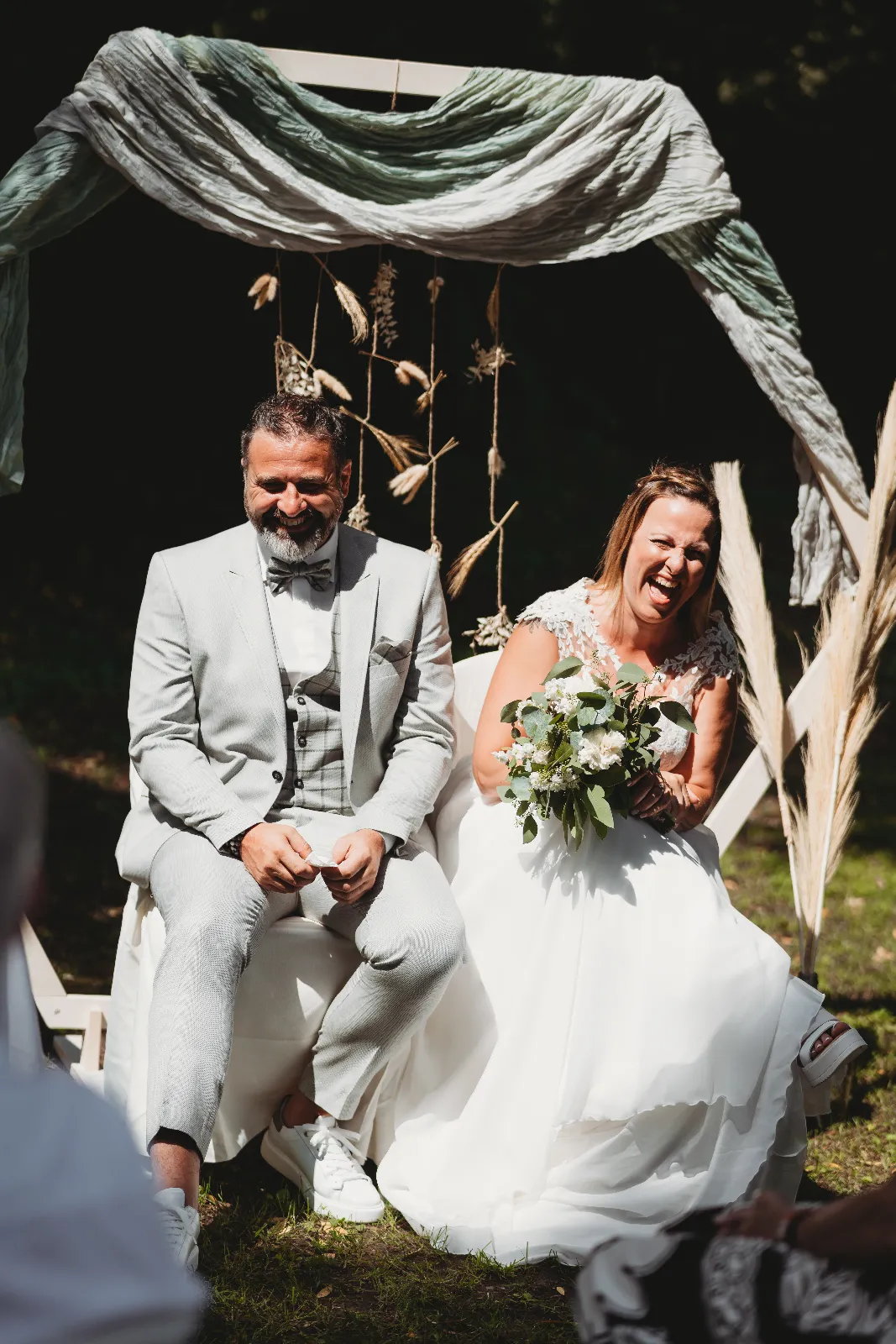 Couple marié assis sous une arche de pampas et eucalyptus pendant leur cérémonie laïque, prestation Vert le Bonheur en Wallonie
