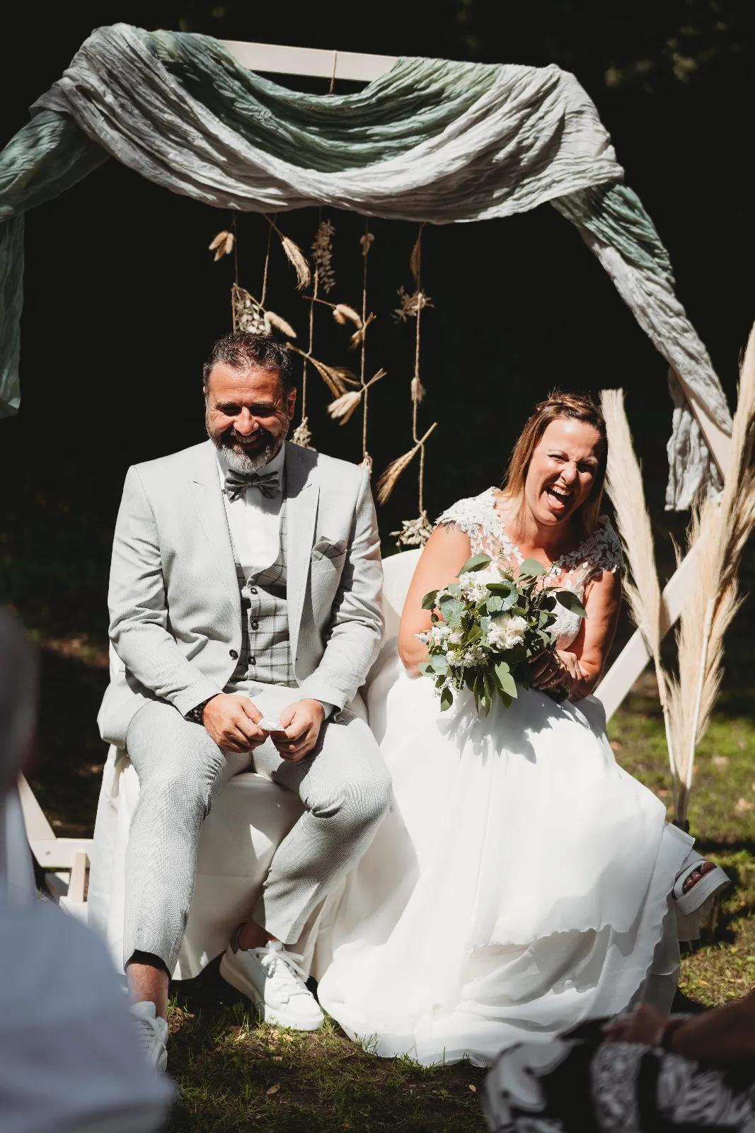 Married couple sitting under an arch of pampas and eucalyptus during their humanist ceremony, Vert le Bonheur service in Wallonia