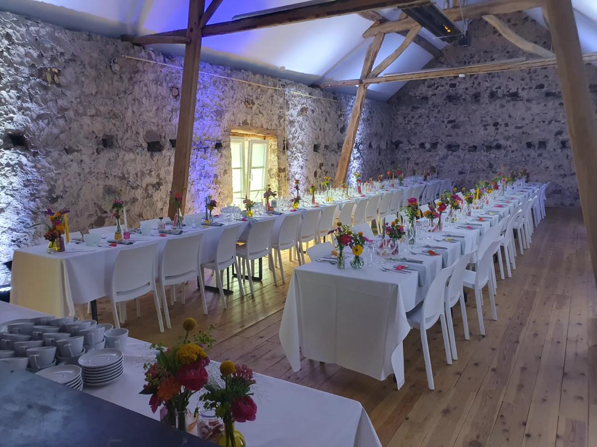 Stone-walled hall at the Ferme du Bois Wiame in Mozet, set with long tables for a wedding