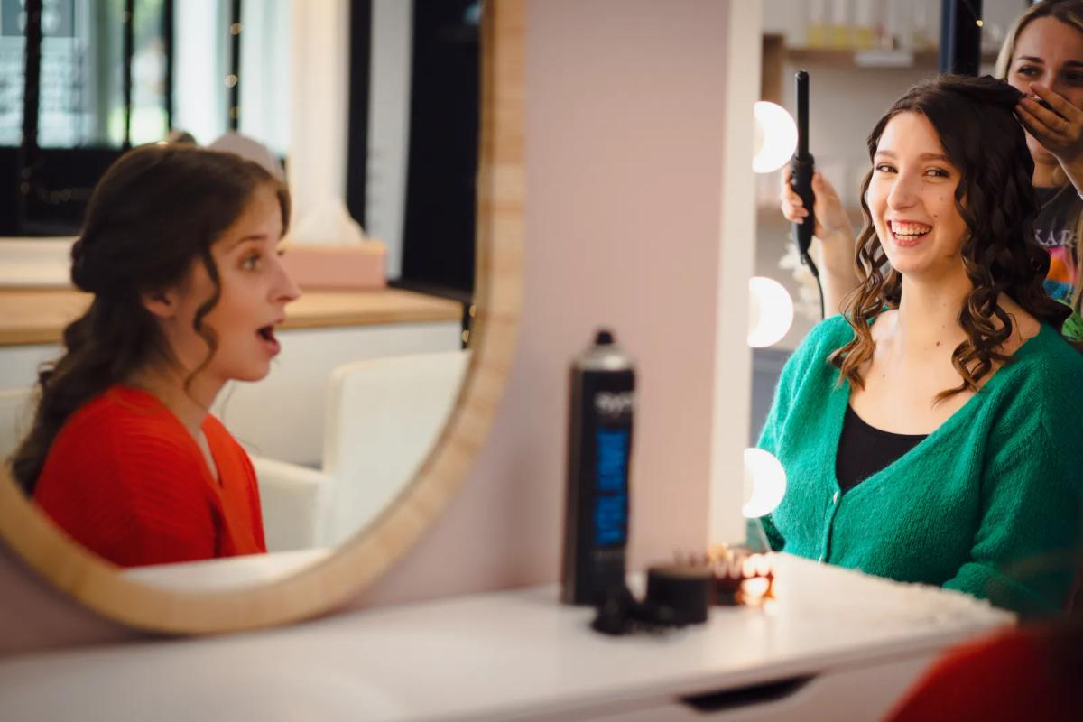 Future mariée en préparation devant un miroir, coiffure et maquillage en cours