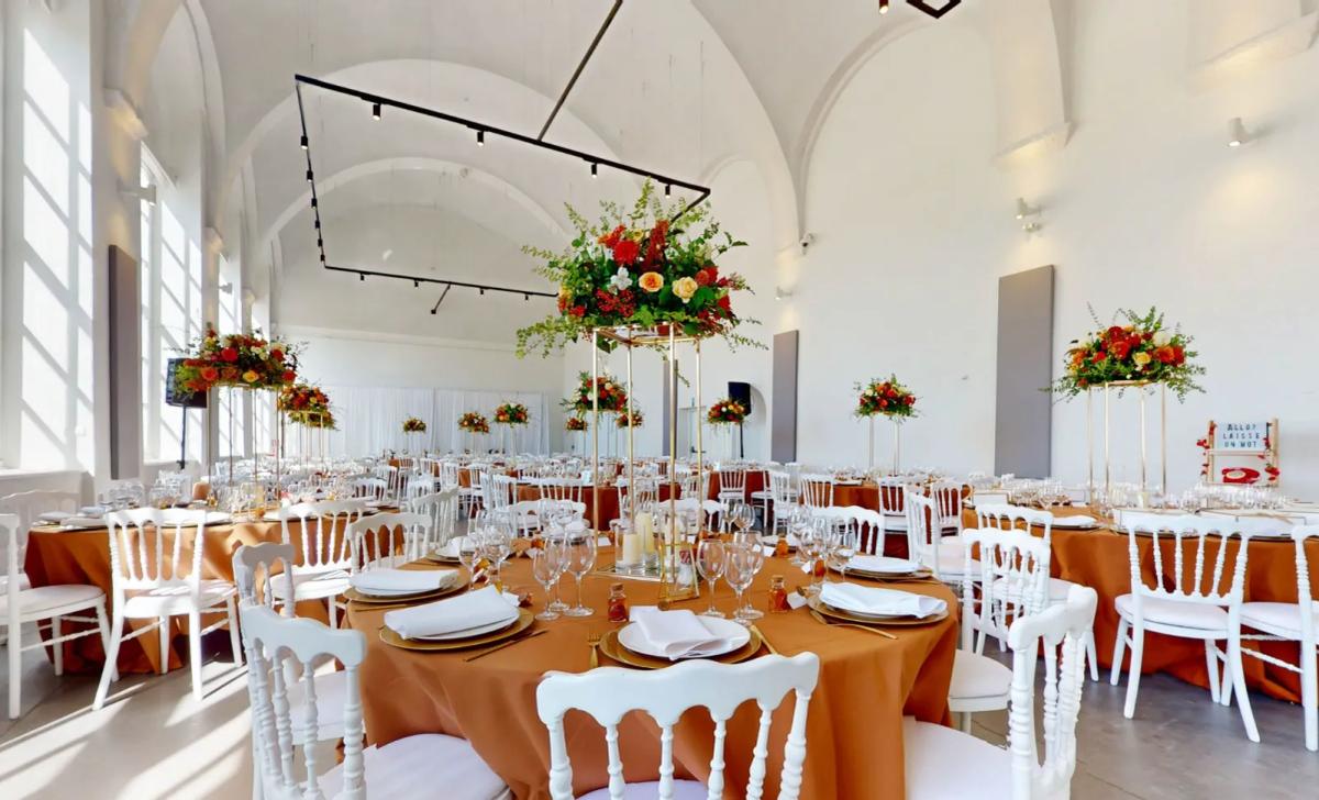 Hall of the Orangerie du Château de Seneffe set up for a wedding with round tables